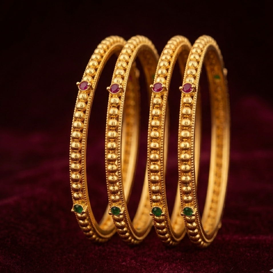 three gold bangles with embedded gemstones on a dark background