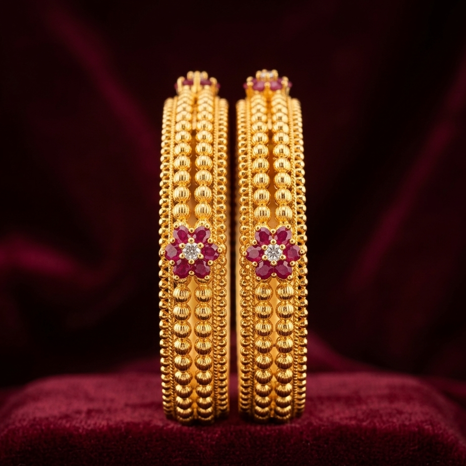 Pair of gold bangles with red stones on a dark background