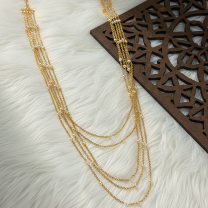 Gold necklace on a textured white surface with a wooden decorative mat
