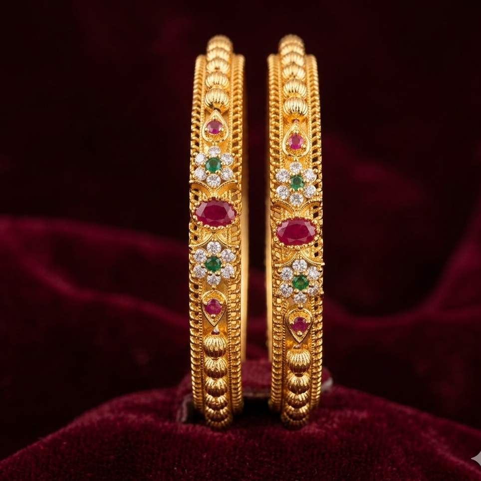 pair of gold bangles with gemstones on a red velvet background