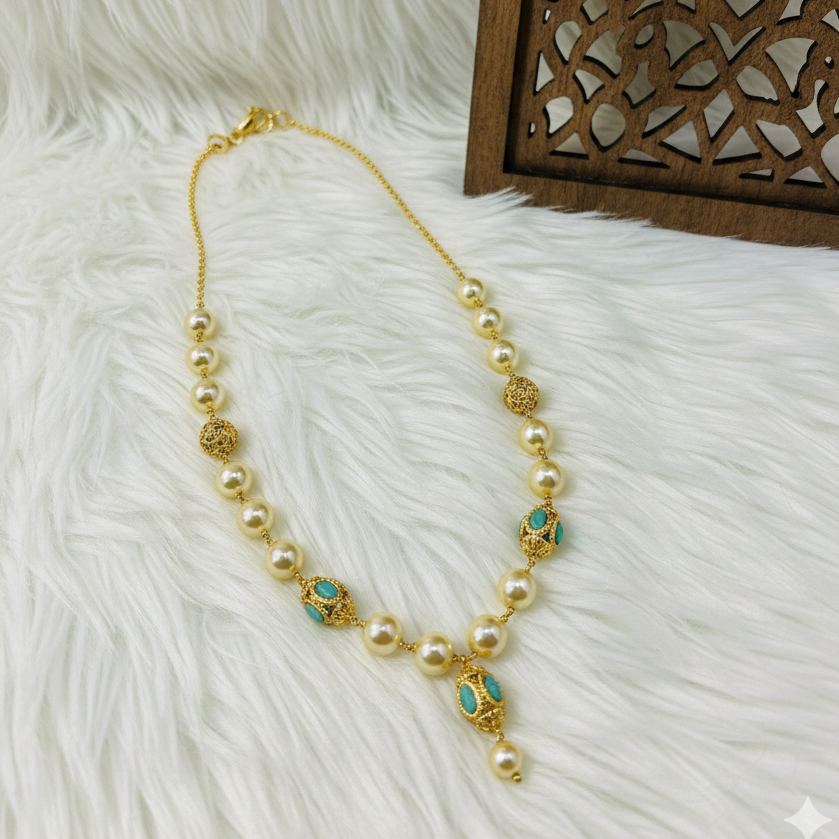 Pearl necklace with gold and blue accents on a white fur surface with a wooden decorative item.